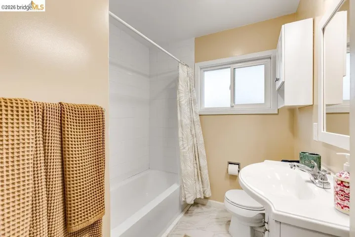 Full bathroom with vanity, shower / bath combo, and light marble finish flooring