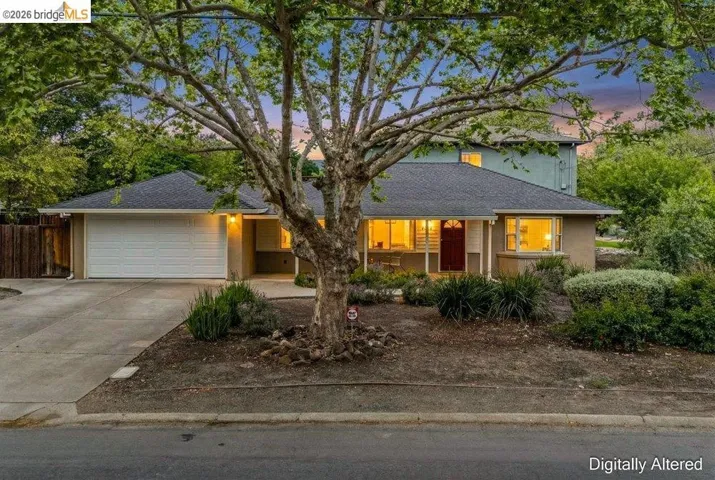 View of front of property featuring an attached garage, concrete driveway, stucco siding, and roof with shingles
