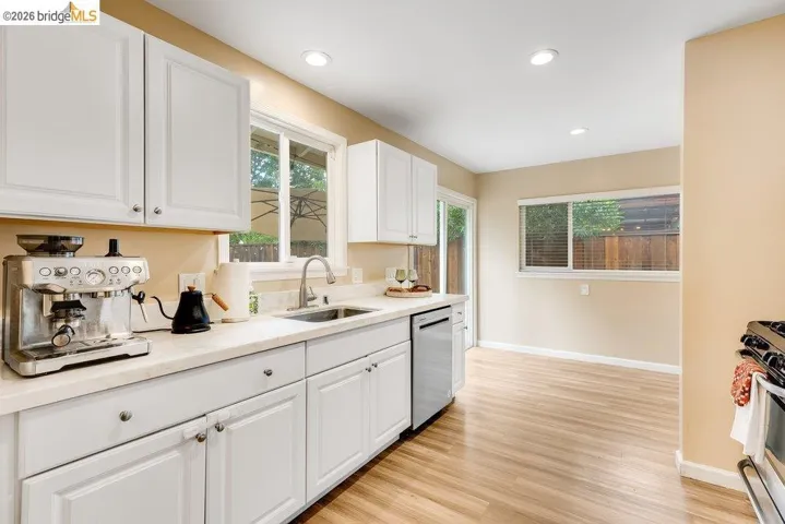 Kitchen featuring white cabinetry, light wood finished floors, stainless steel appliances, recessed lighting, and light stone countertops