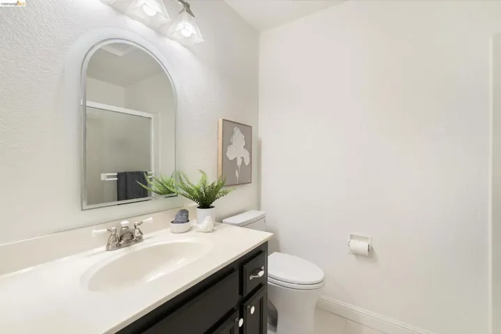 Full bathroom with vanity, a shower stall, a textured wall, and light tile patterned floors