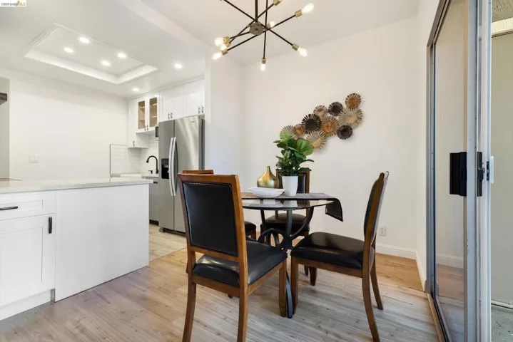 Dining room with hanging lights, light wood-style flooring, and a tray ceiling