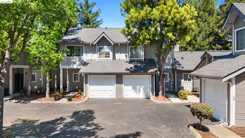 View of front of home with a shingled roof, driveway, and a garage