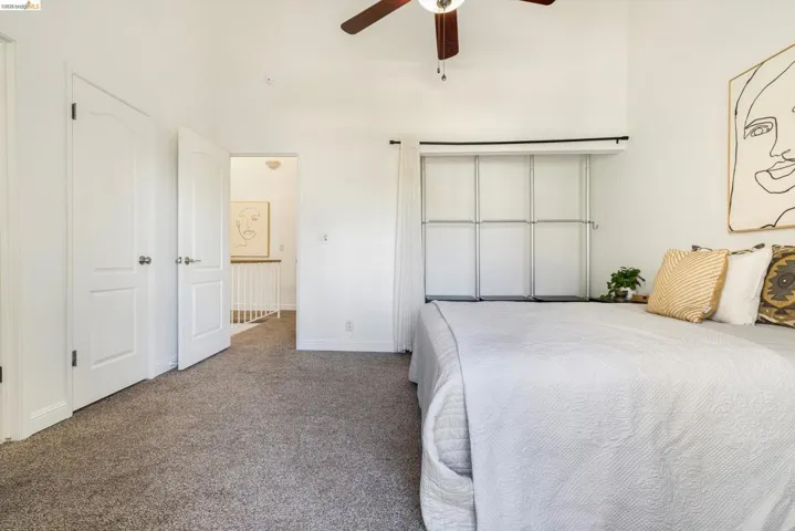 Carpeted bedroom featuring ceiling fan and a high ceiling