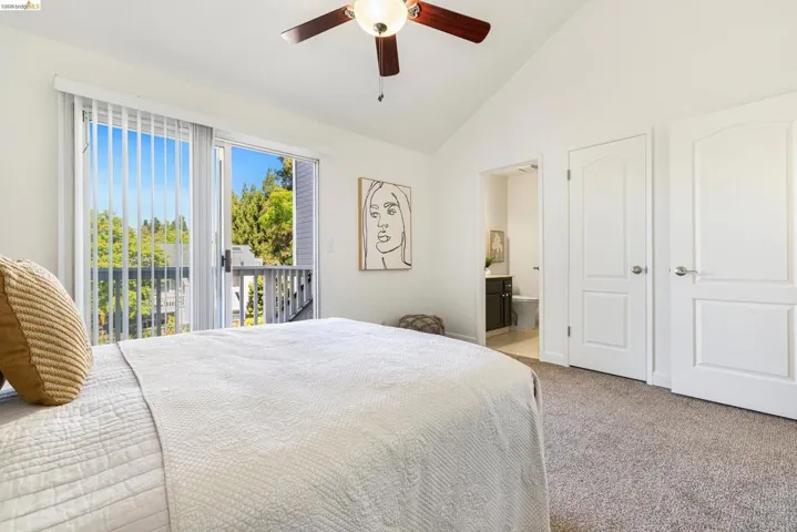 Carpeted bedroom featuring lofted ceiling, access to exterior, a ceiling fan, and ensuite bathroom