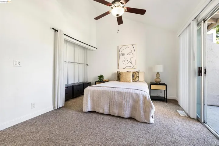 Carpeted bedroom featuring vaulted ceiling, access to exterior, and a ceiling fan