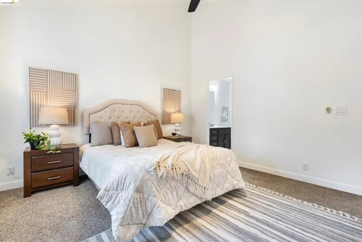 Bedroom featuring a high ceiling, carpet, connected bathroom, and ceiling fan