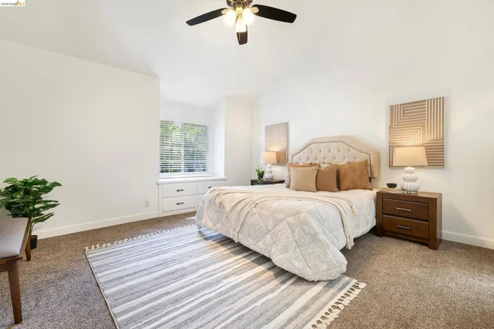 Carpeted bedroom with ceiling fan and lofted ceiling