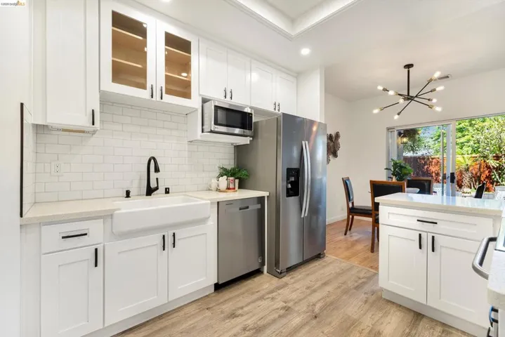 Kitchen featuring white cabinetry, light stone counters, stainless steel appliances, and light wood finished floors