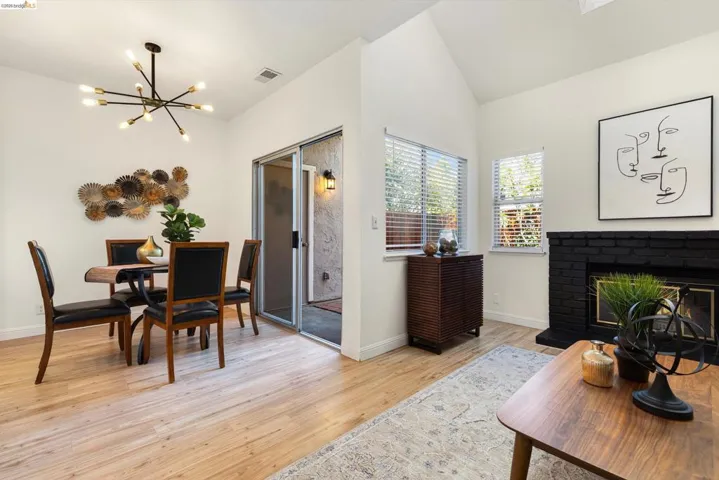 Dining area with hanging lights, light wood-style flooring, lofted ceiling, and a brick fireplace