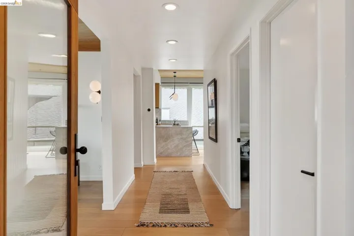 Hall with light wood-type flooring and recessed lighting