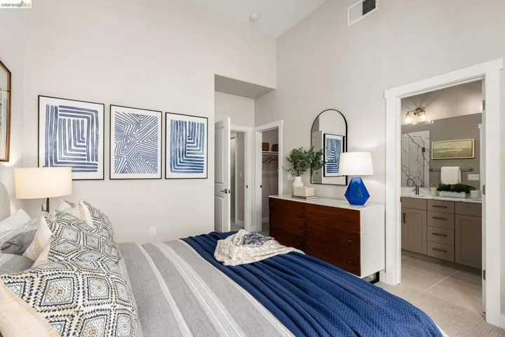 Bedroom with a high ceiling, a walk in closet, light tile patterned floors, and ensuite bathroom