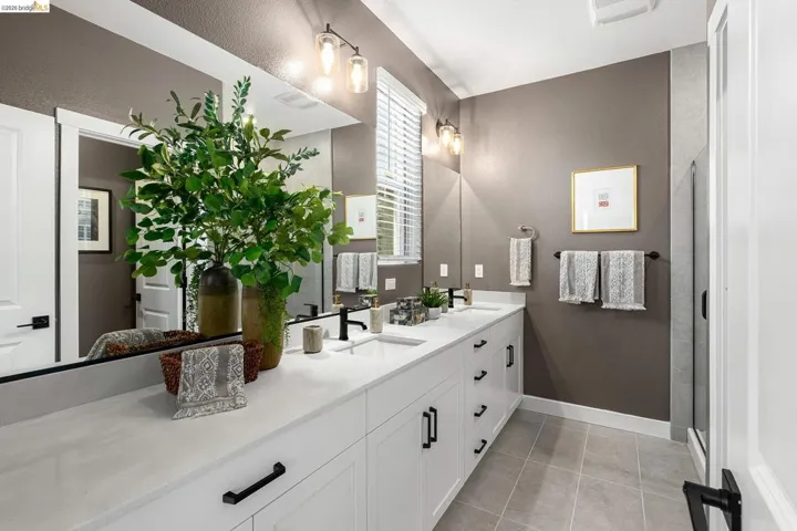 Full bath featuring double vanity, tile patterned flooring, and a shower with shower door