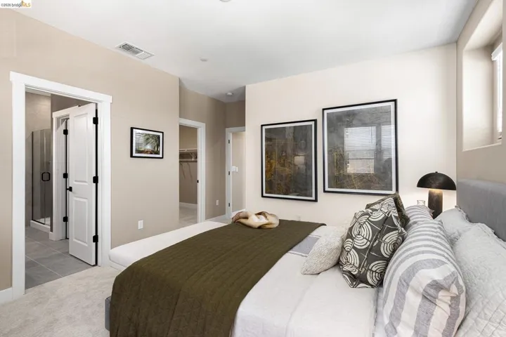 Tiled bedroom featuring a walk in closet, carpet, and ensuite bath