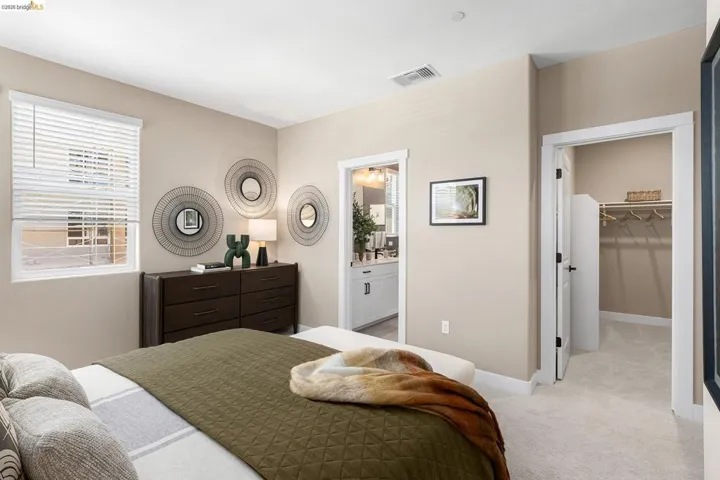 Bedroom featuring light carpet, a walk in closet, and connected bathroom