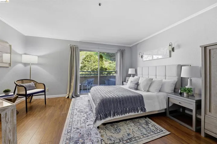 Bedroom featuring a textured wall, dark wood-type flooring, access to outside, and crown molding