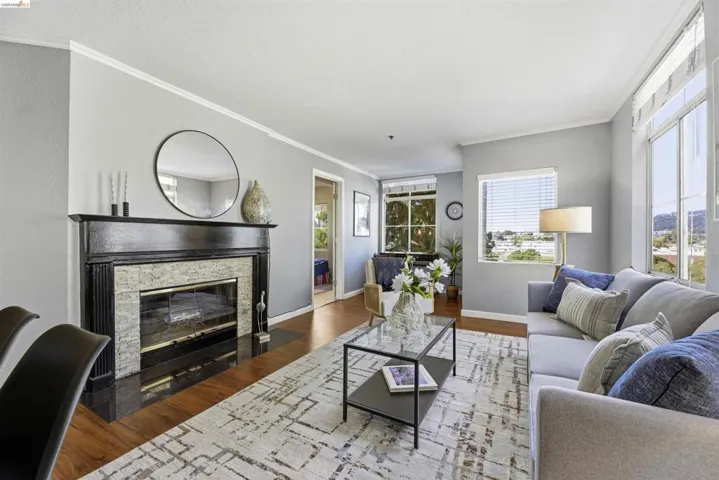 Living room featuring wood finished floors, plenty of natural light, a fireplace, and ornamental molding