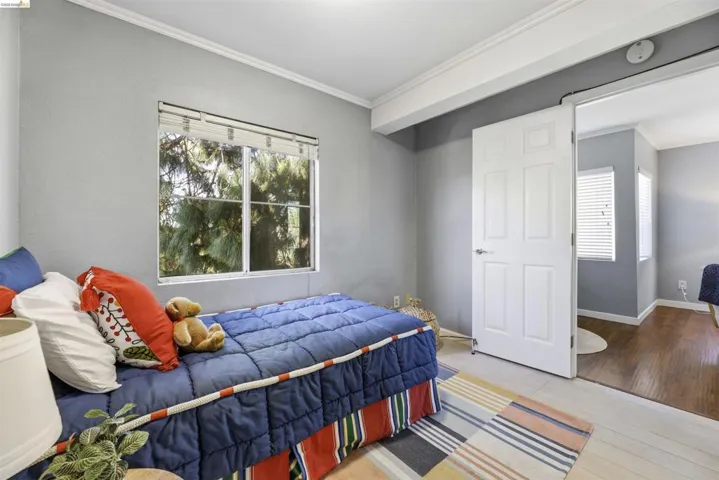 Bedroom featuring ornamental molding, multiple windows, and light wood-type flooring