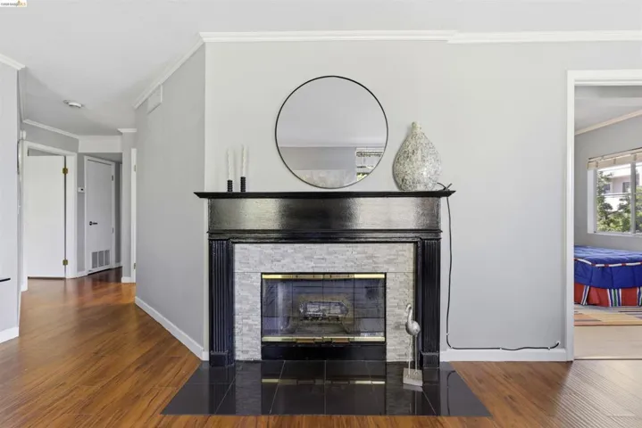 Detailed view of ornamental molding, wood finished floors, and a stone fireplace