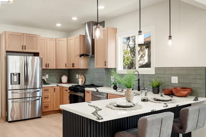 Kitchen with appliances with stainless steel finishes, a peninsula, hanging light fixtures, a kitchen bar, and light brown cabinets