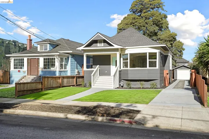 Bungalow-style house featuring an outbuilding, a shingled roof, a garage, a porch, and concrete driveway