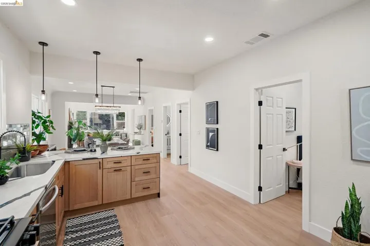 Kitchen with a peninsula, light stone countertops, decorative light fixtures, light wood-type flooring, and dishwasher