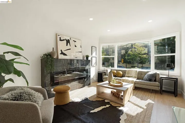 Living room with wood finished floors, recessed lighting, and a high end fireplace