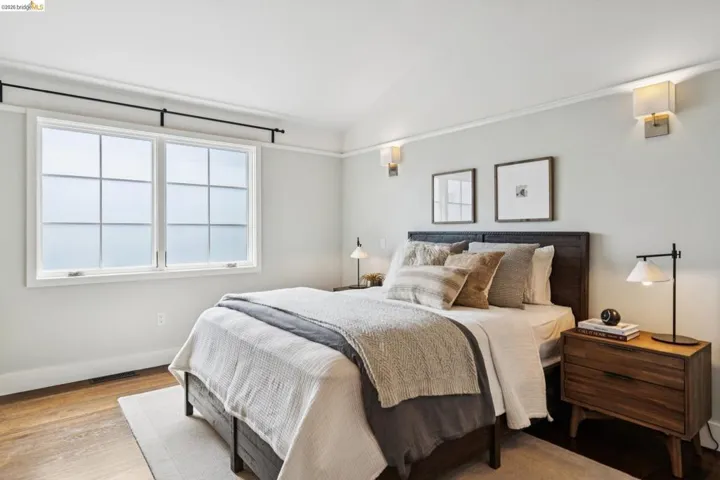 Bedroom featuring vaulted ceiling, light wood finished floors, and multiple windows