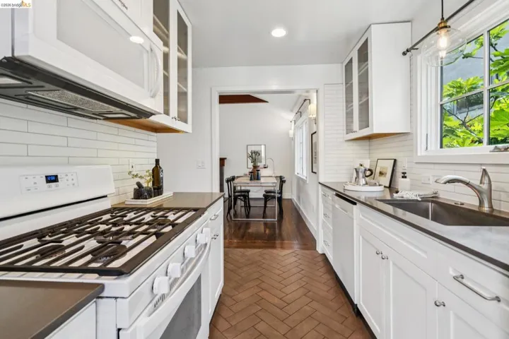 Kitchen with white appliances, glass insert cabinets, brick floors, and white cabinets
