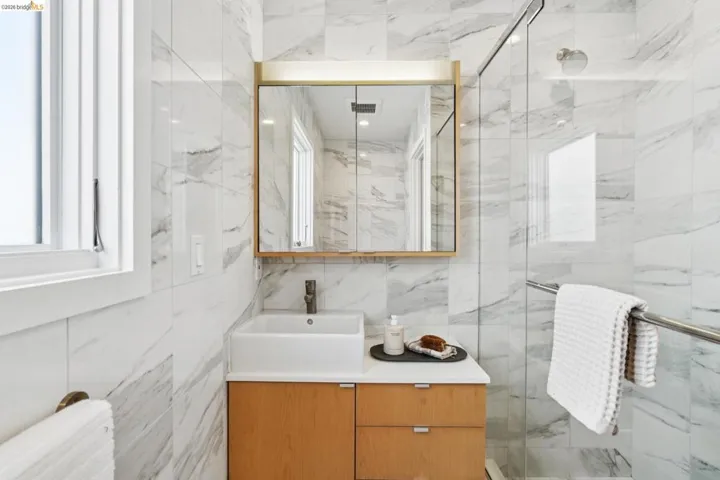 Bathroom with vanity, tile walls, and a marble finish shower