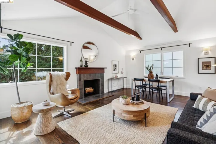 Living area featuring a fireplace, wood finished floors, vaulted ceiling, and a ceiling fan