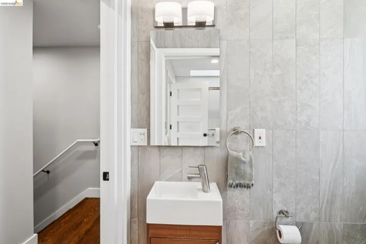 Bathroom featuring vanity, tile walls, and dark wood-style flooring