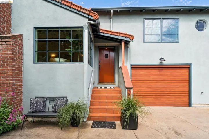 Doorway to property featuring stucco siding, an attached garage, a tile roof, and driveway