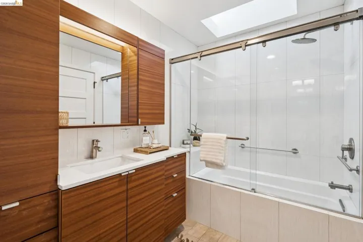 Bathroom featuring vanity, tiled shower / bath, and a skylight