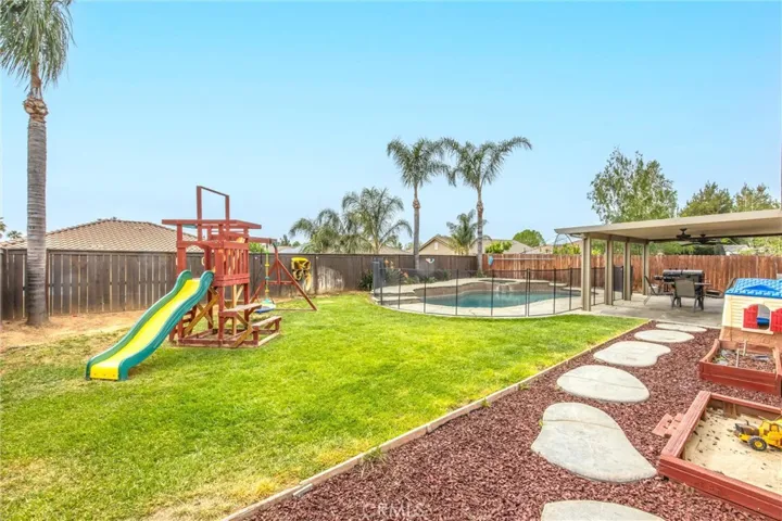 Lush grass with wooden playset and swimming pool/spa