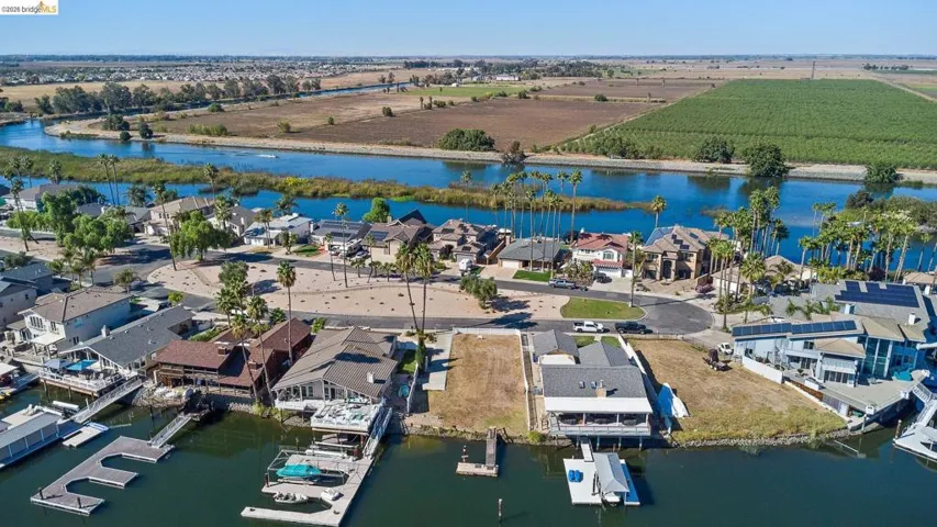 Aerial view of sparsely populated area featuring a large body of water, nearby suburban area, and extensive farmland