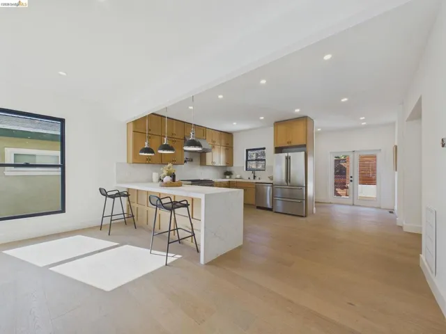 Kitchen featuring a kitchen breakfast bar, a peninsula, stainless steel appliances, light wood-type flooring, and pendant lighting