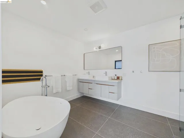 Full bath with double vanity, a soaking tub, and recessed lighting