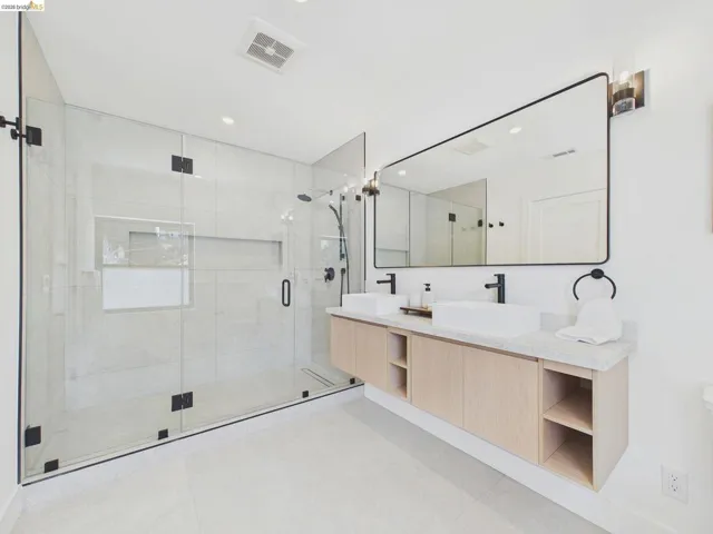 Bathroom with double vanity, a shower stall, and recessed lighting