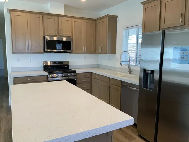 Kitchen featuring stainless steel appliances, light wood-style floors, and light stone counters