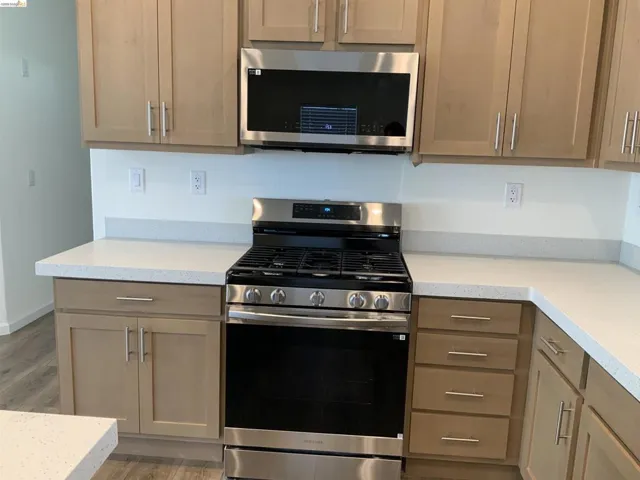 Kitchen featuring stainless steel appliances, light wood-style floors, and light stone countertops
