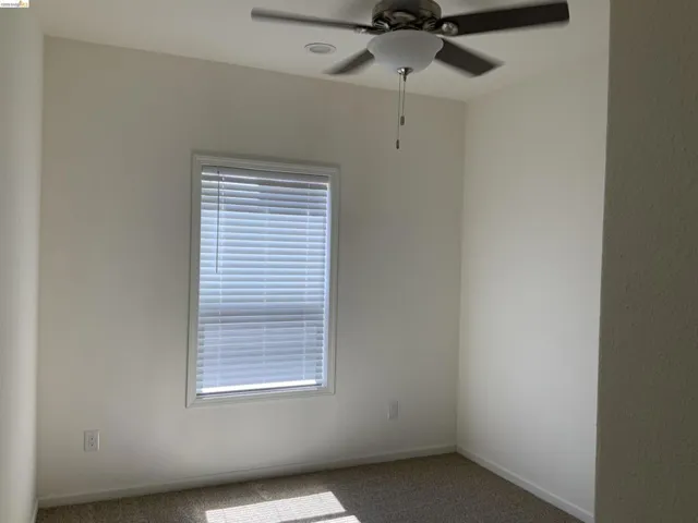 Carpeted spare room with a ceiling fan and baseboards