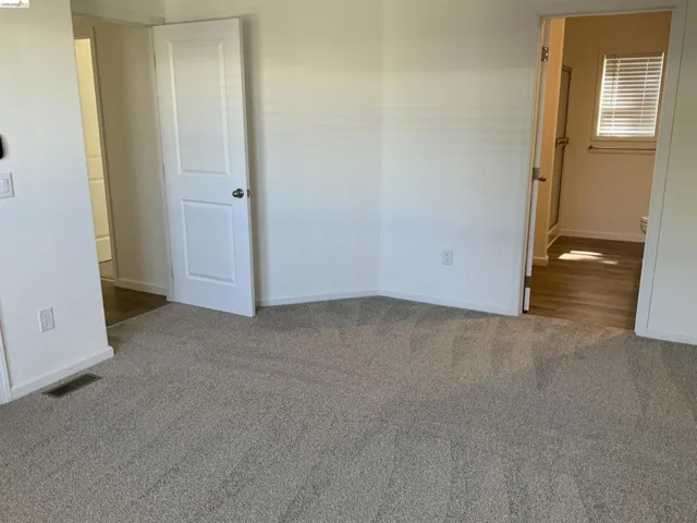 Unfurnished bedroom with dark carpet and baseboards