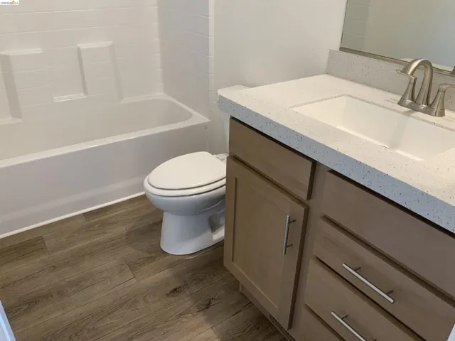 Bathroom with vanity, dark wood-style floors, and bathing tub / shower combination