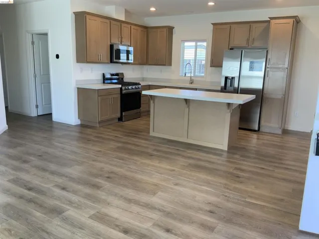 Kitchen featuring stainless steel appliances, light countertops, recessed lighting, wood finish cabinetry, and light wood-style floors