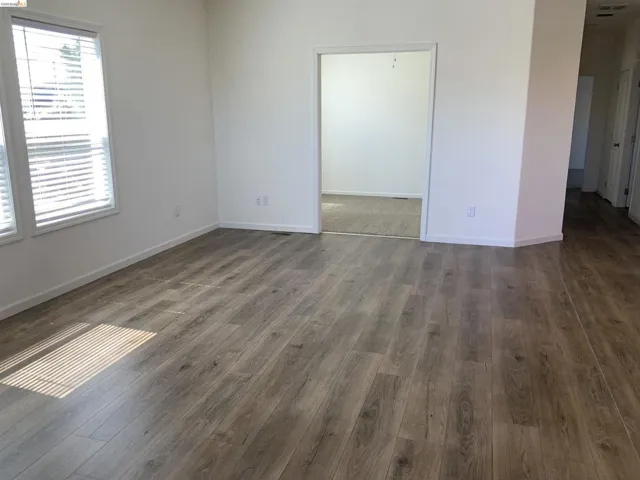 Empty room featuring baseboards and dark wood-type flooring