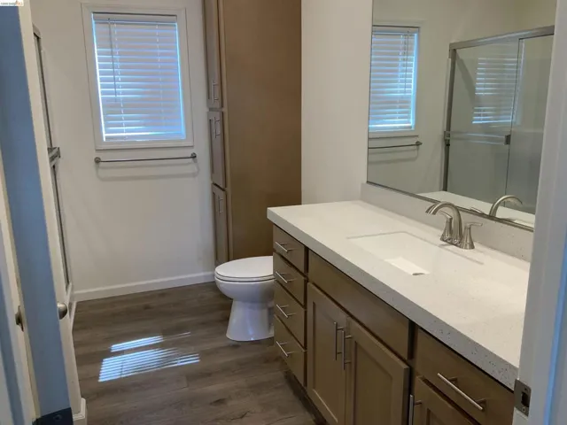 Full bath with vanity, dark wood finished floors, and a stall shower