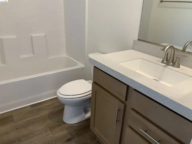 Full bathroom with dark wood-type flooring, vanity, and shower / tub combination