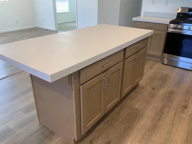 Kitchen with light wood-type flooring, stainless steel range with gas stovetop, a kitchen island, and open floor plan