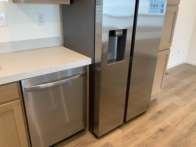 Kitchen featuring stainless steel appliances, light wood-style flooring, and light stone counters