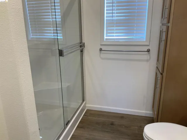 Full bath with a stall shower and dark wood finished floors